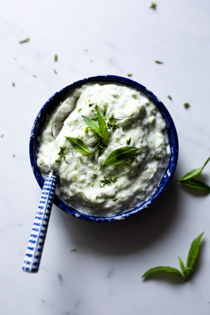 Tzatziki in a blue bowl with a spoon.