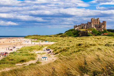 Bamburgh Castle overlooking a busy beach.