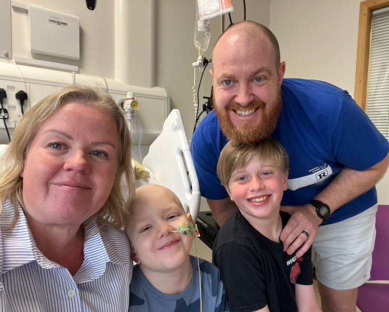 Family photo of a young boy in a hospital bed with his parents.