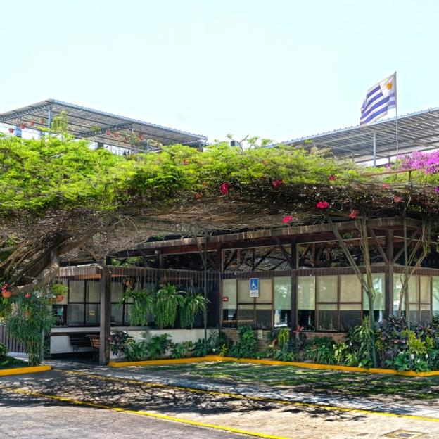 Restaurant building with a tree canopy overhead and a Uruguayan flag visible.