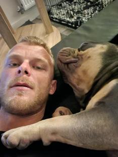 Man and XL Bully dog lying together.