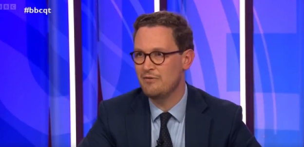 Man in suit and glasses speaking.