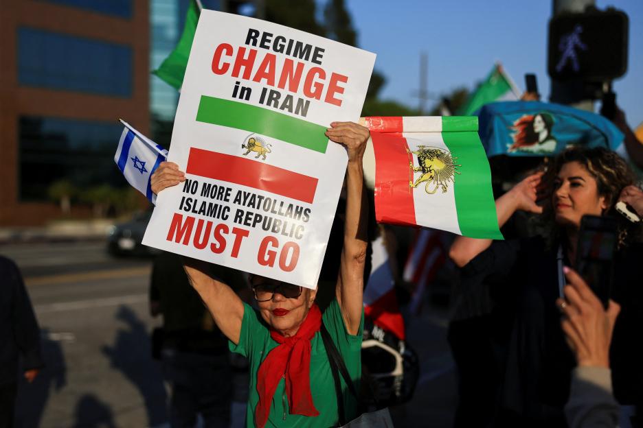 Protestor holding Israeli and pre-Islamic Republic Iranian flags and a sign that reads