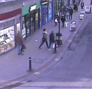 CCTV footage of pedestrians on a city street.