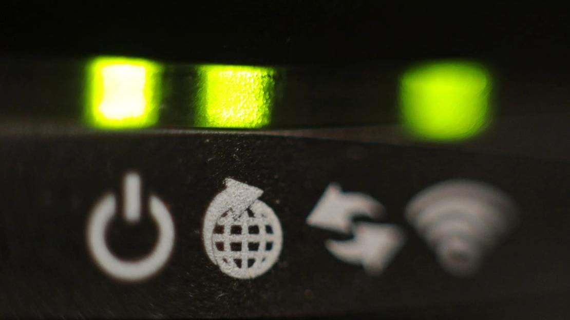 Close-up of a broadband router's illuminated indicator lights and symbols.