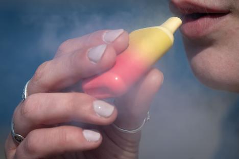 Woman vaping a disposable e-cigarette.