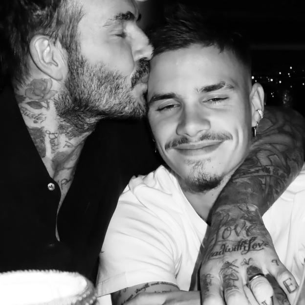 Black and white photo of David Beckham kissing his son Romeo on the forehead.