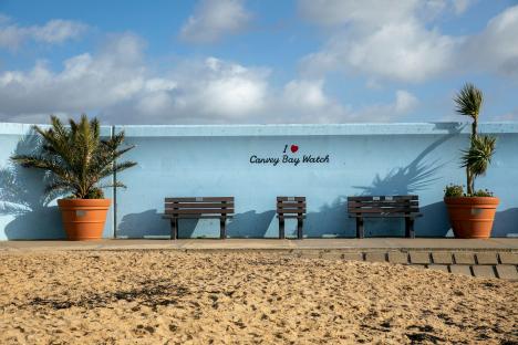 Three benches sit in front of a light blue wall that reads