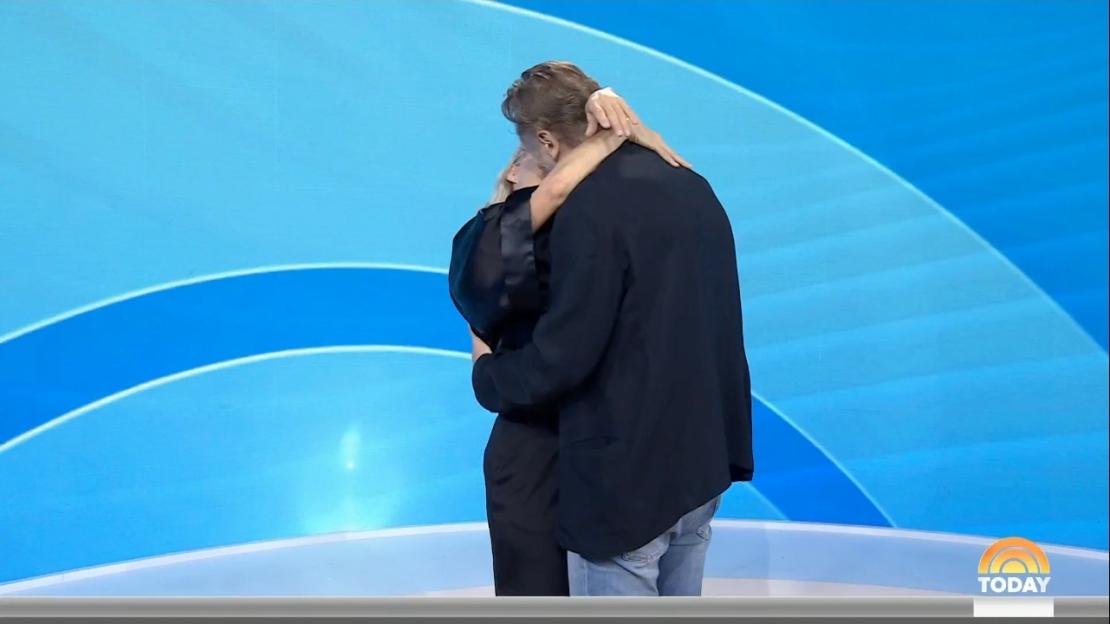 Pamela Anderson and Liam Neeson embracing on a television show.