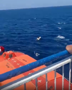 Small boat in the ocean near a life raft.
