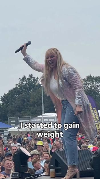 Liz McClarnon on stage, singing into a microphone, with text overlay