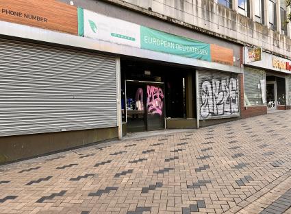Graffiti-covered storefront with closed metal shutters.