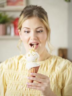 Woman looking surprised at a potato ice cream cone topped with potato sticks.