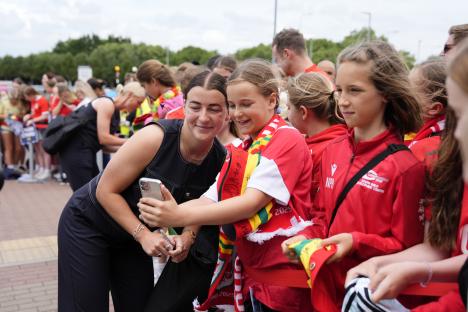 Angharad James taking a selfie with young Wales fans at an airport.
