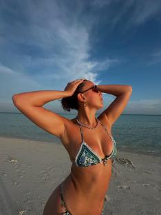 Woman in bikini on beach looking at sky.