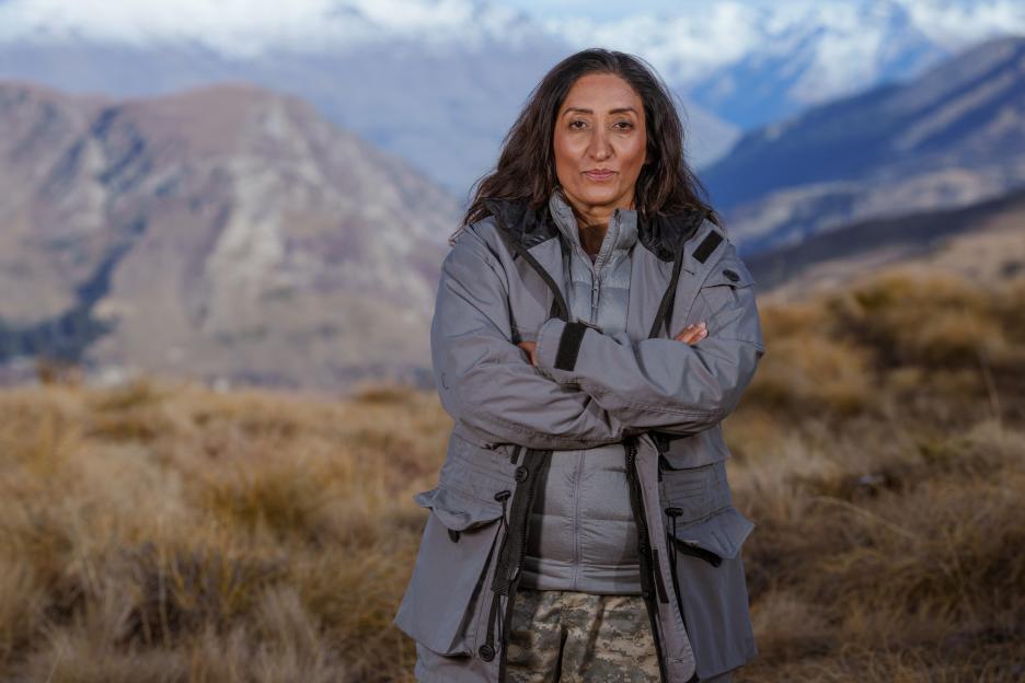 Shazia Mirza standing outdoors with mountains in the background.