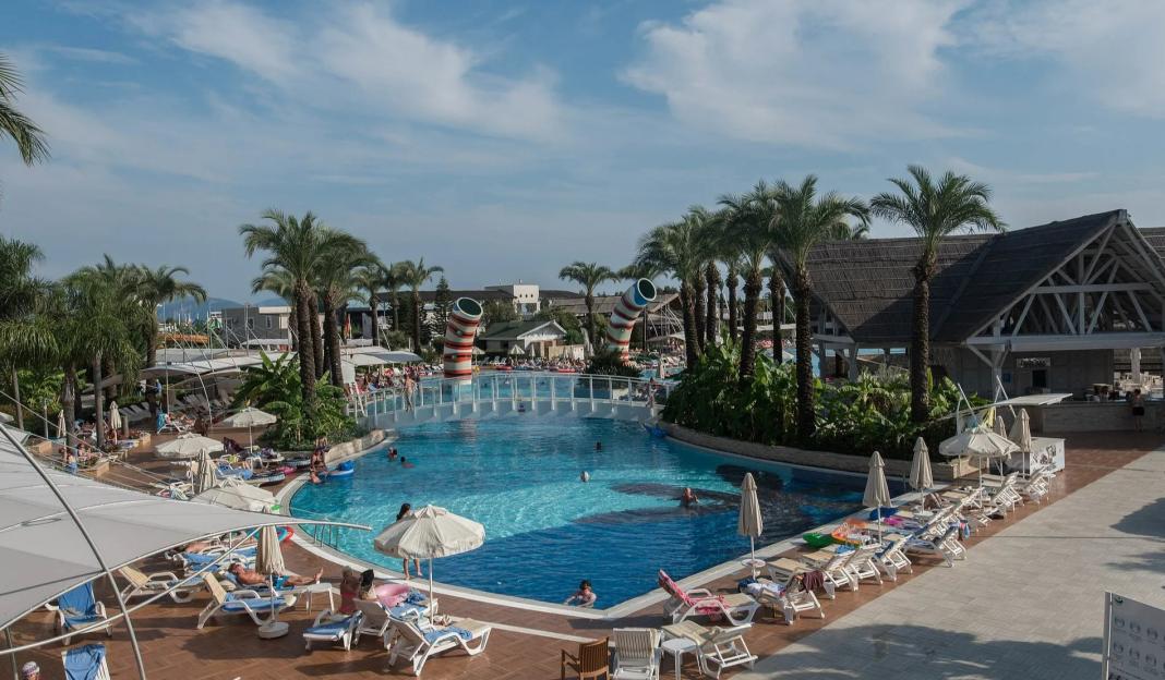Resort pool with surrounding lounge chairs and palm trees.