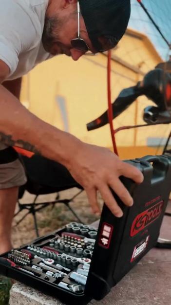 A man opens a toolbox filled with tools.