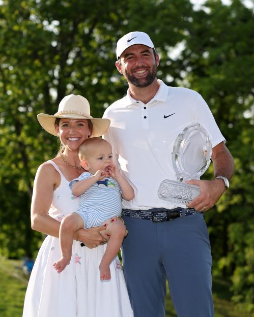 Scottie Scheffler with his wife and son, holding a golf trophy.
