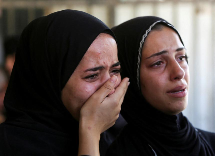 Two women in head scarves weep.