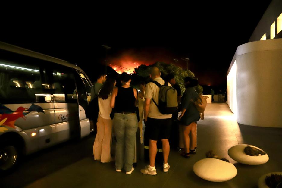 Tourists evacuating a hotel during a wildfire at night.