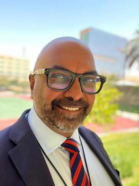 Headshot of a man in a suit and glasses.