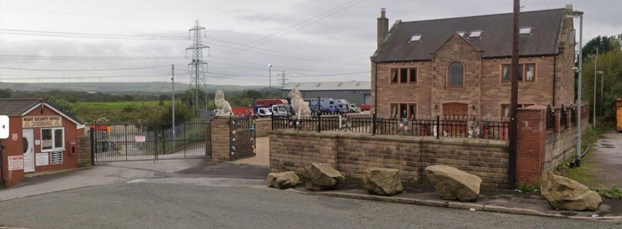Large house on a scrapyard with lion statues guarding the entrance.