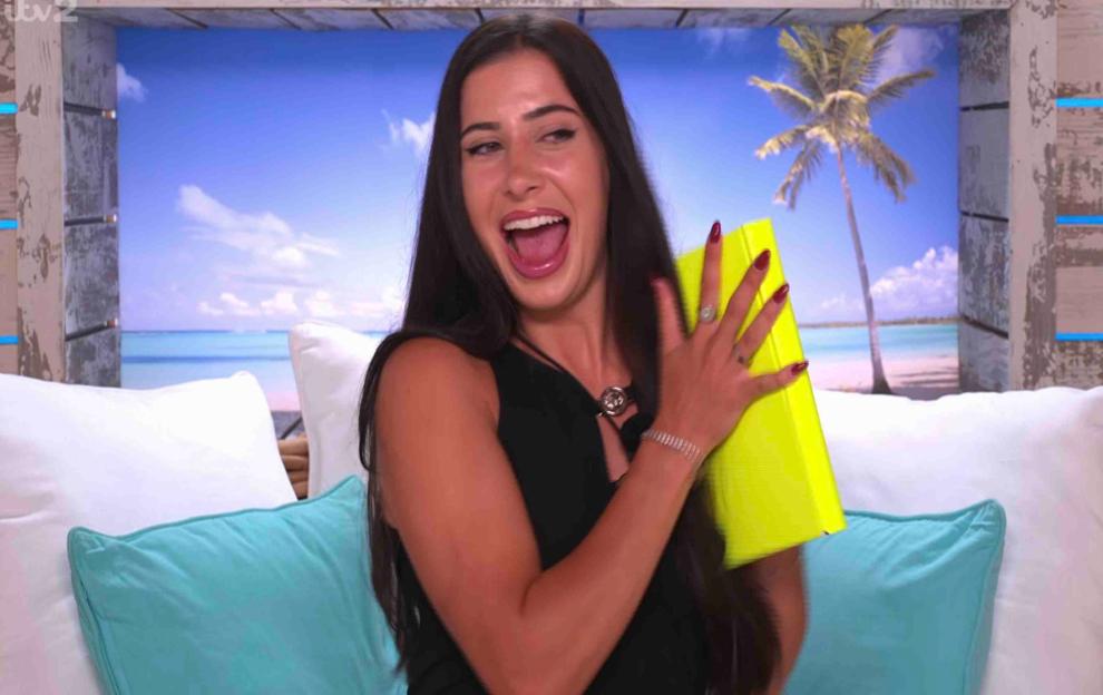 A woman excitedly holds a bright yellow book.