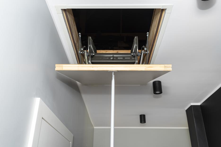 Closed attic access with folding metal stairs.