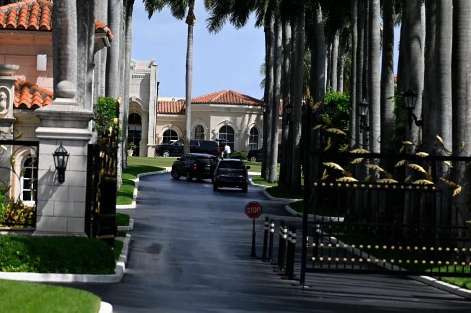 Driveway leading to a luxury estate with black SUVs.
