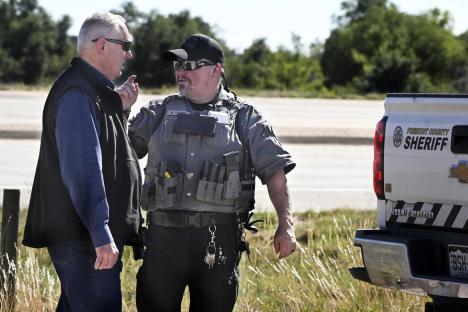 Sheriff and man in discussion at funeral home investigation.