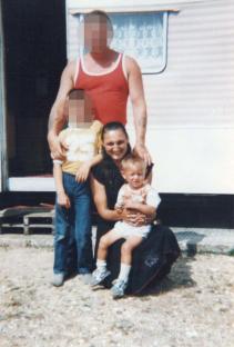 Photo of a family in front of a caravan; the faces of the adults and one child are blurred.