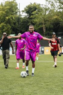 Alex Iwobi with a soccer ball on a field.