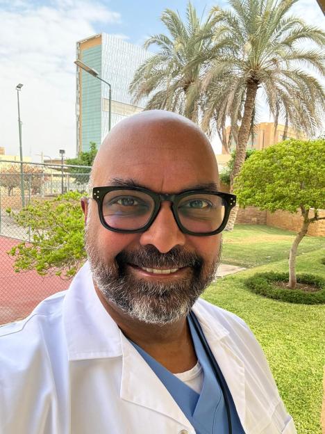A doctor in a white coat smiles for a selfie.