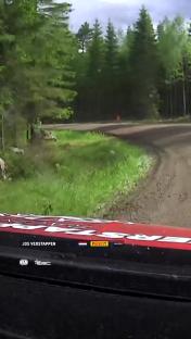 Jos Verstappen's car driving on a dirt road through a forest.
