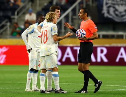 Referee speaking with RB Salzburg players on the soccer field.