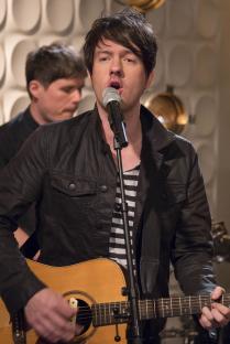 a man singing into a microphone while playing a guitar
