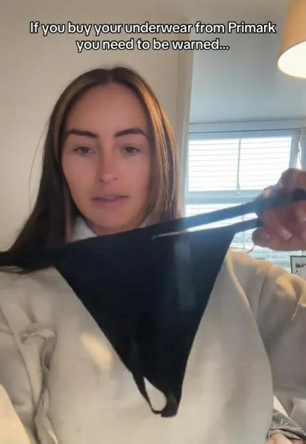 Woman holding up and showing a pair of Primark thongs that have broken.