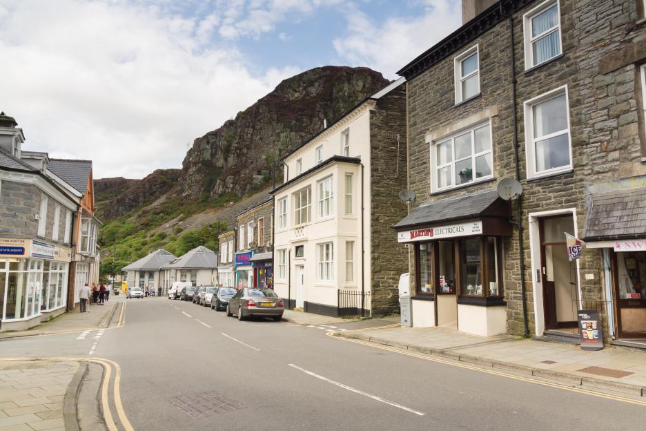 Street scene in Blaenau Ffestiniog, Wales, with shops and slate mines in the background.