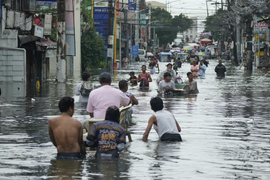 Residents wade through a flooded street in Malabon City, Philippines.