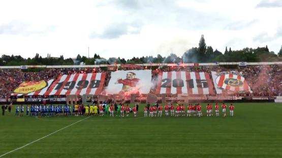 Soccer fans displaying a large banner in a stadium.