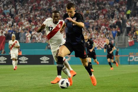 Ivan Perisic of Croatia vying for the ball against a Peruvian player during a soccer match.
