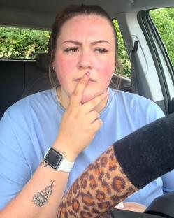 Woman in a car, looking thoughtful.
