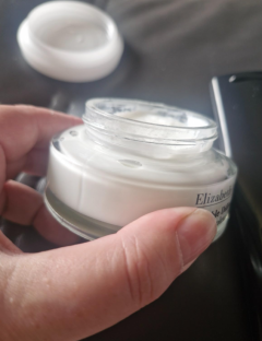 A hand holding a jar of Elizabeth Arden Visible Difference hydrating cream.
