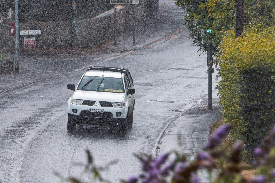 White pickup truck driving on a rain-soaked road.