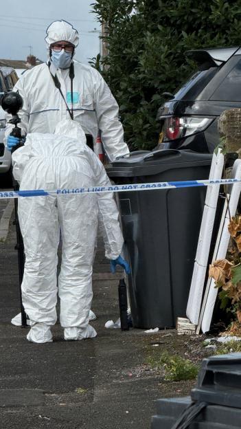 Forensic investigators in protective suits examining a crime scene.