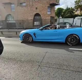 A light blue convertible driving down a London street.