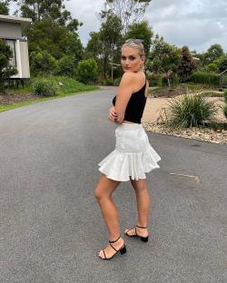 Woman in black top and white skirt.