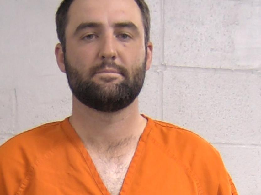 Mugshot of Scottie Scheffler in an orange jumpsuit.