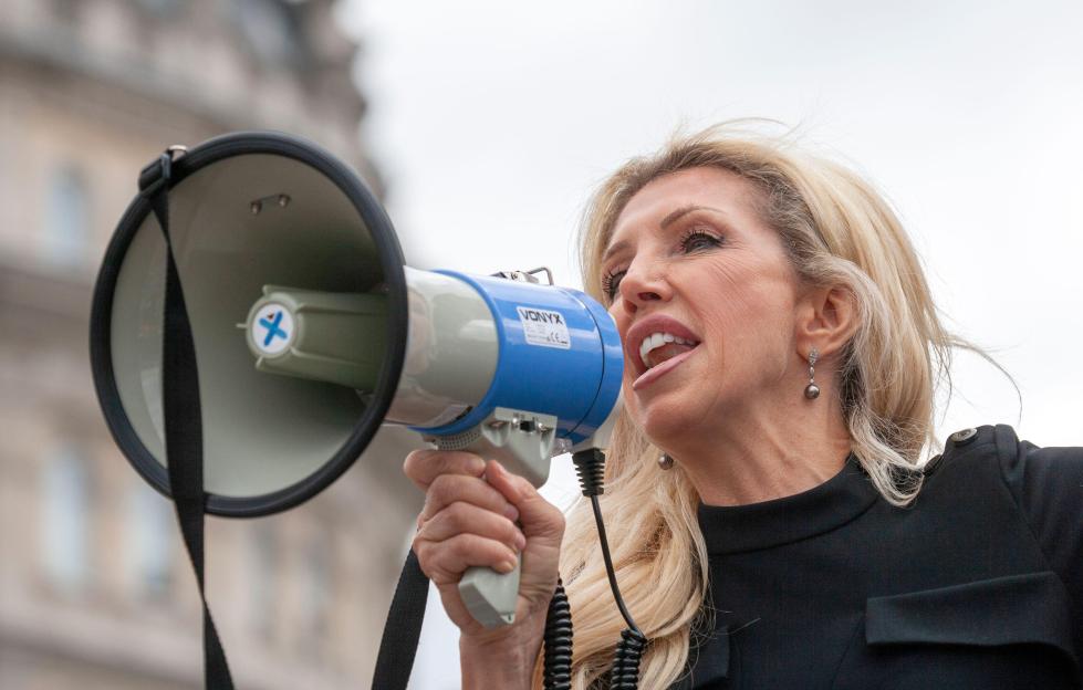 Woman speaking into megaphone at protest against lockdowns.